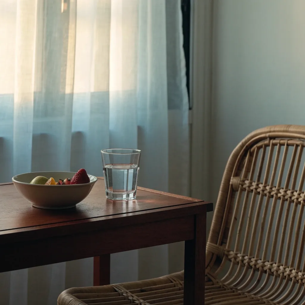 A family meal table seen from behind, hands passing a bowl of rice and a platter of vegetables