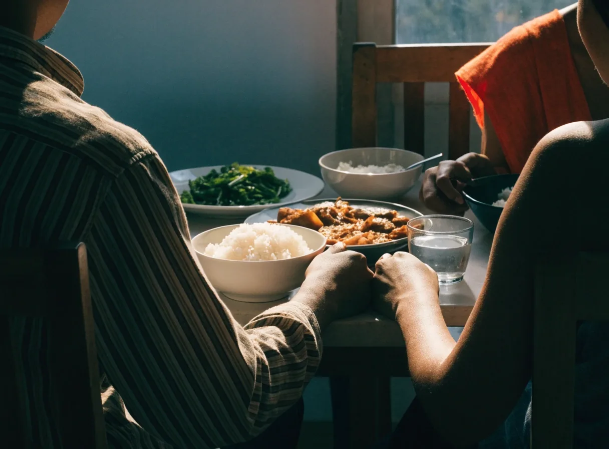 Family meal table seen from behind with shared dishes in warm window light